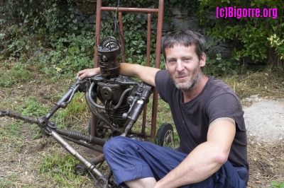 Pedro Fremy assis aux coté de Vétéran dans le jardin de son atelier à Agos-Vidalos/ Stéphane Boularand (c)Bigorre.org